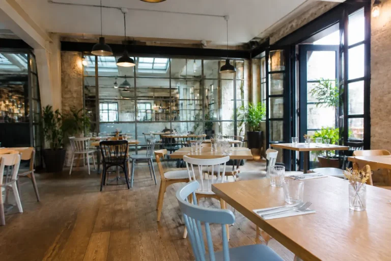 Restaurant au style industriel avec tables en bois et plantes pour une déco harmonieuse.