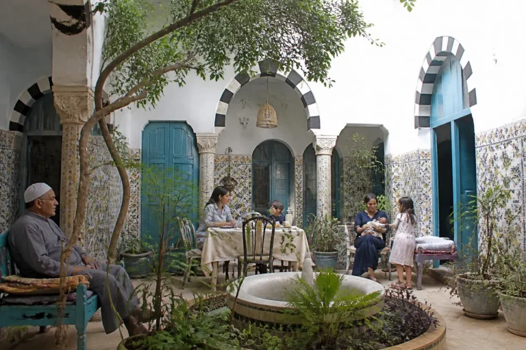 Famille réunie dans une cour intérieure d'une maison traditionnelle tunisienne richement décorée