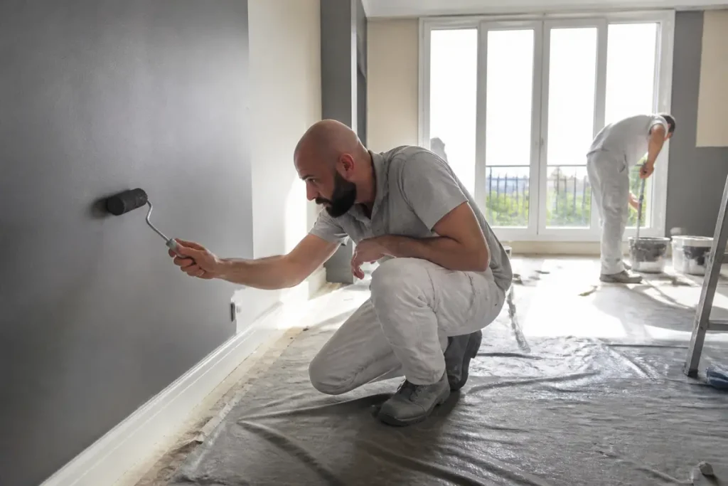 Deux hommes appliquent de la peinture murale pour renovimmopro.fr rénovation intérieure.